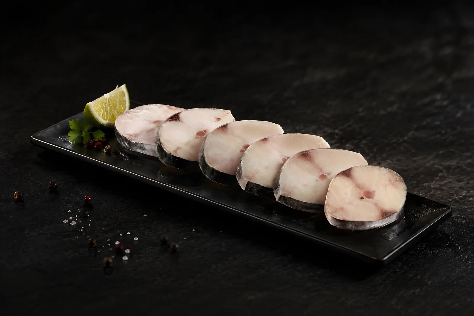Fish steaks on a slate plate with lime